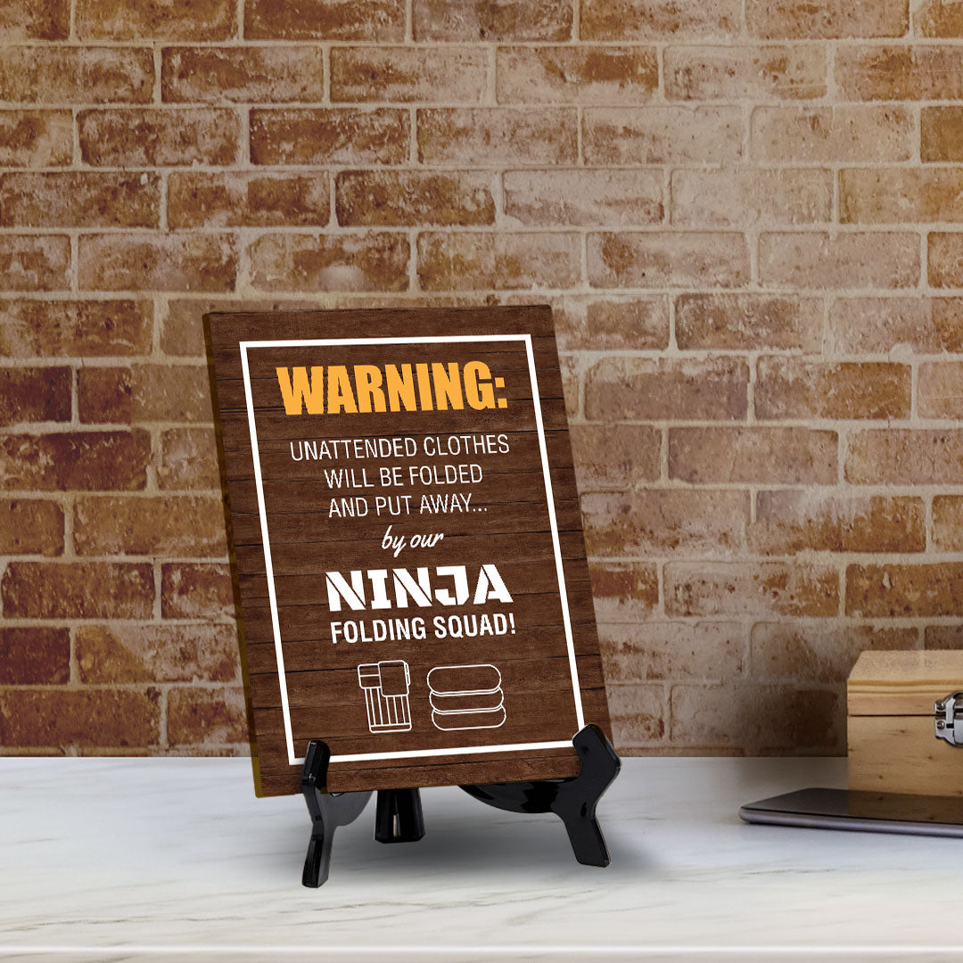 Signs ByLITA Warning: Unattended clothes will be folded and put away... by our ninja folding squad! Table Sign with Acrylic Stand (6x8“)